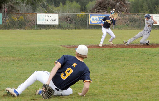Forks shortstop Landen Olson (9) made a great play on a hard hit ground ball then while falling down, throwing Ilwaco’s runner Ethan Hopkins (45) out on a force place by second basemen Dylan Micheau. (Lonnie Archibald/for Peninsula Daily News