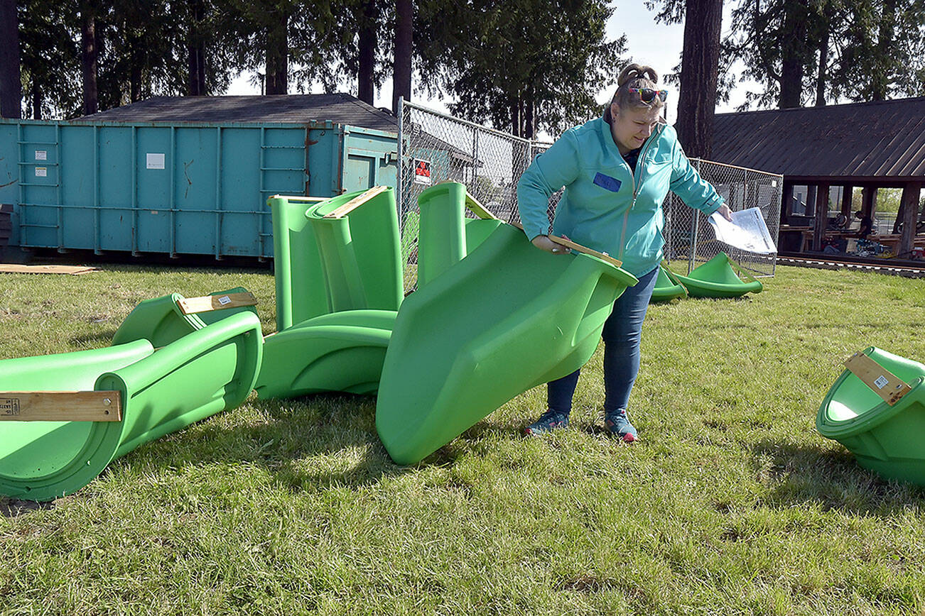 Roxanne Pfiefer-Fisher, a volunteer with a team from Walmart, sorts through sections of what will become a slide during Wednesday’s opening day of a community rebuild of the Dream Playground at Erickson Playfield in Port Angeles. (Keith Thorpe/Peninsula Daily News)