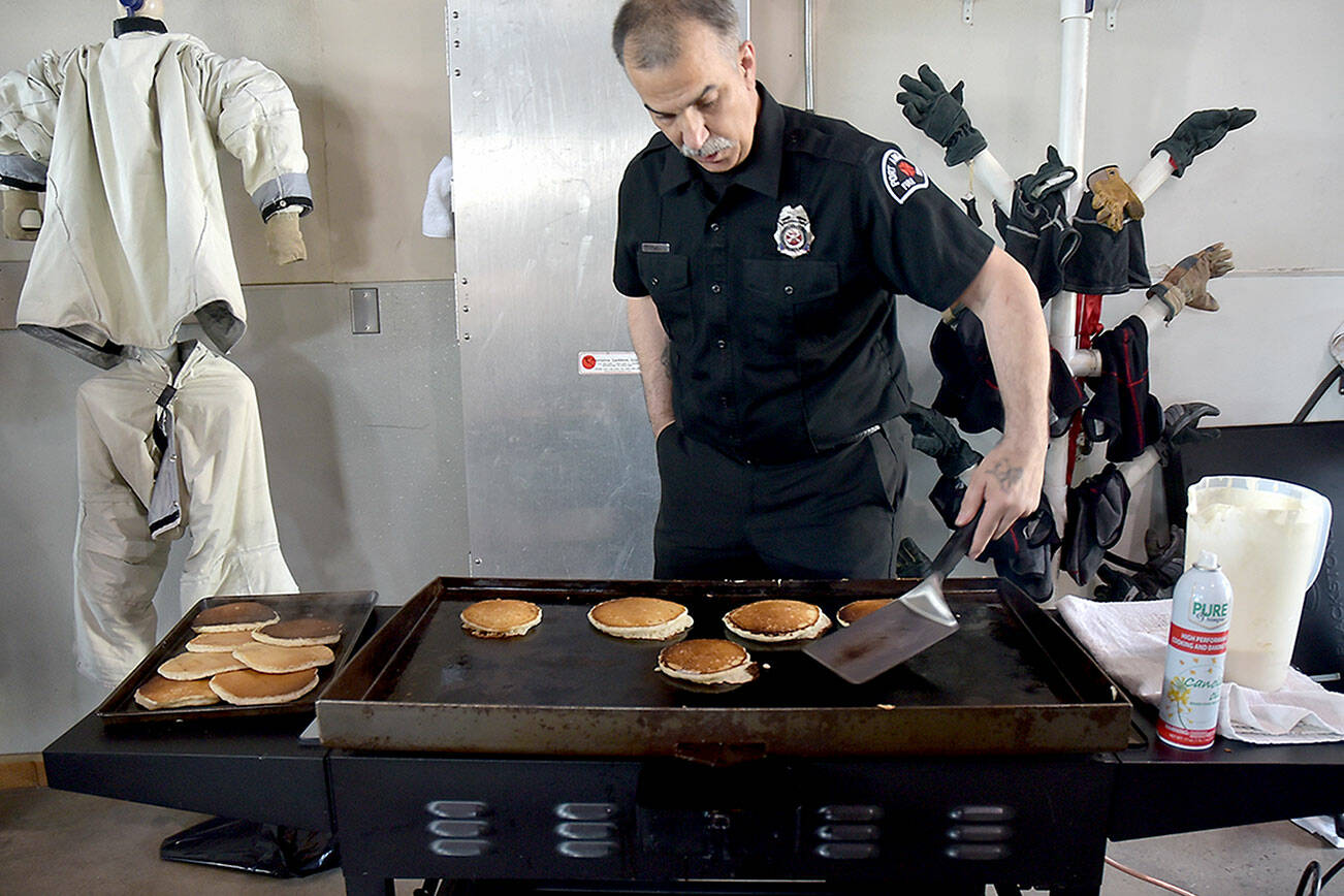 Port Angeles Fire Department community paramedic Brian Gerdes flips pancakes during Saturday’s annual breakfast on Saturday at the fire hall. The event, hosted by the fire department and auxiliary, was a fundraiser for department scholarships and relief baskets. (Keith Thorpe/Peninsula Daily News)