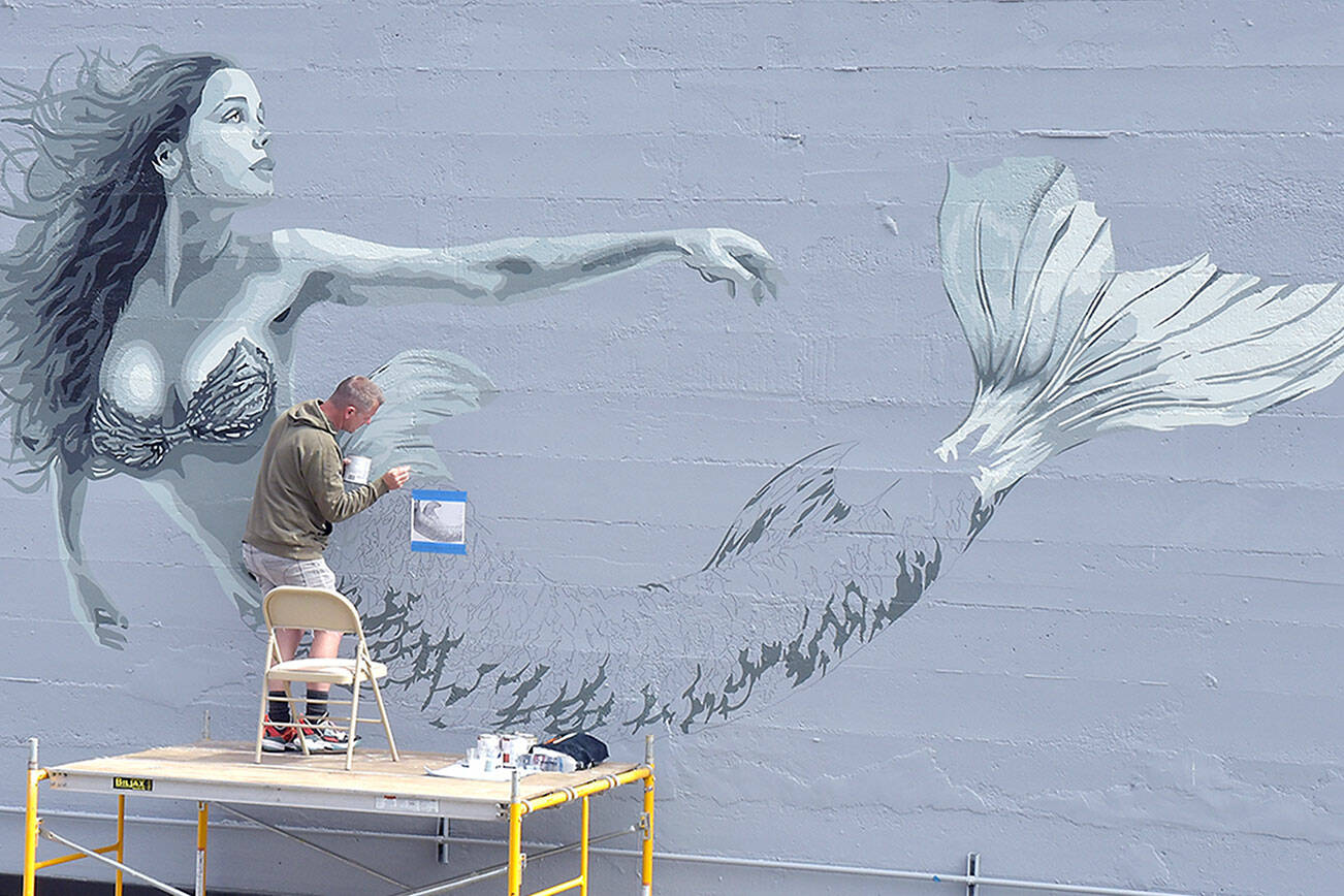 Artist Christopher Keywood of San Diego creates a mermaid mural on the north side of HarborTowne Mall in downtown Port Angeles on Thursday. Keywood, along with the mall's owner, decided that the blank wall deserved a decoration visible from The Gateway transit center and nearby North Lincoln Street. (Keith Thorpe/Peninsula Daily News)