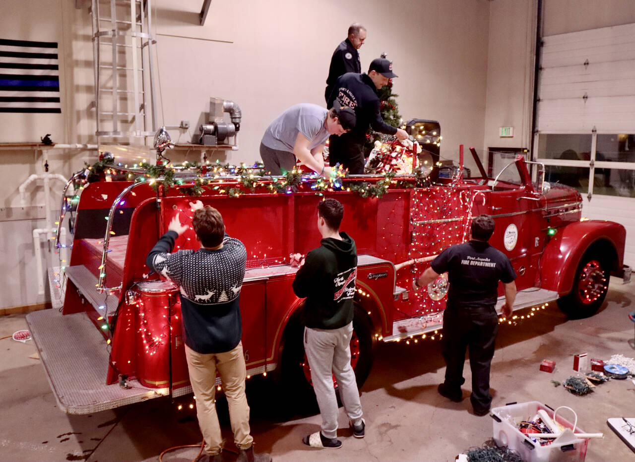 Santas elves, better known as the Port Angeles Fire Department, decorate their vintage 1956 Seagrave fire engine to get ready for the six-day Operation Candy Cane. This will be the 39th annual trek through the streets of Port Angeles to collect donations for area food banks. (Dave Logan/for Peninsula Daily News)
