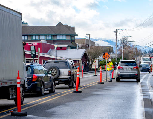 Shannon Story of Port Angeles, an employee of ACI construction in Tacoma, directs traffic on Water Street in Port Townsend on Wednesday as heavy equipment is jostled around the job site. The company is replacing a 100-year-old sewer pipeline with larger and stronger materials. (Steve Mullensky/for Peninsula Daily News)