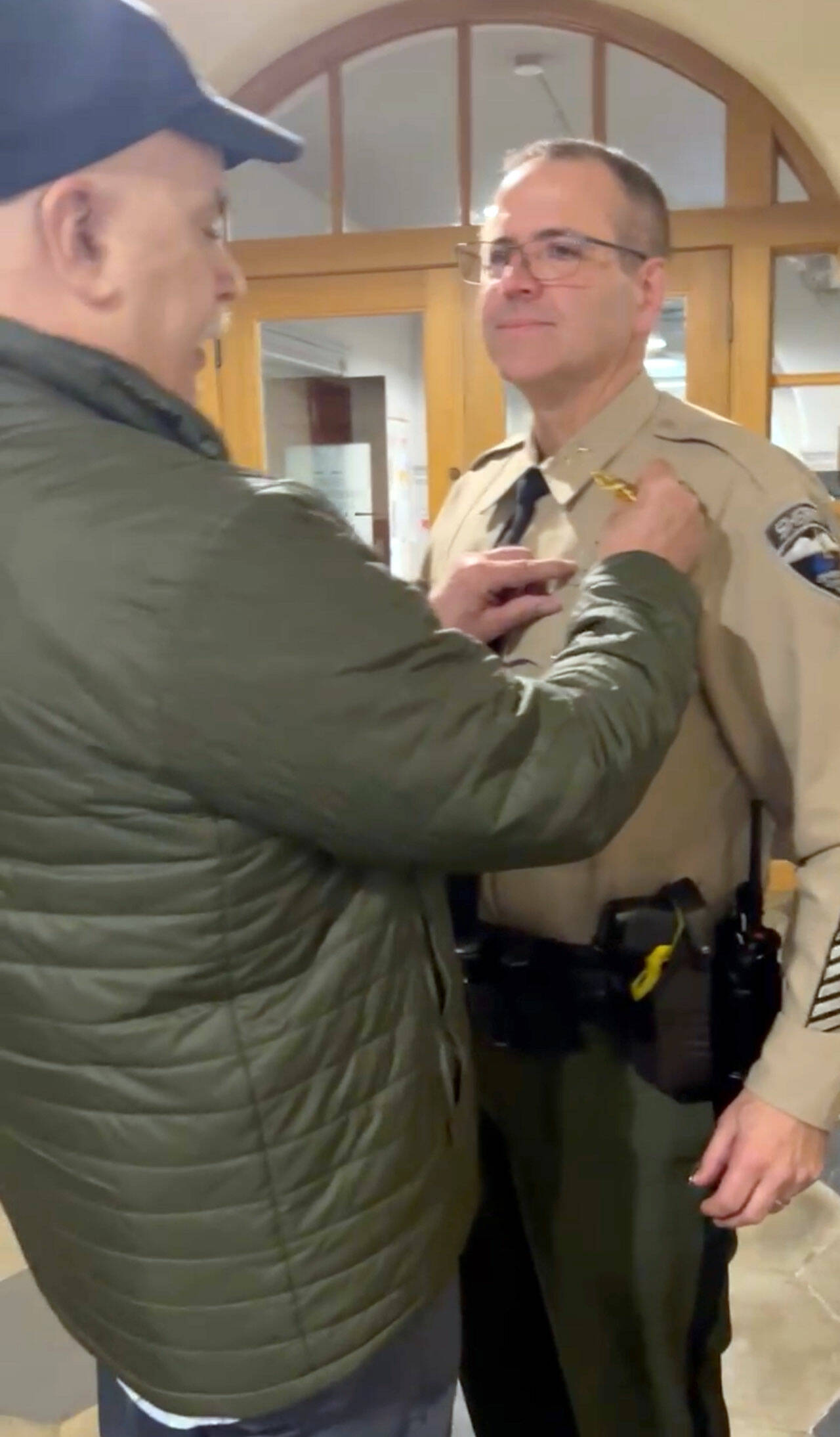 Retired Sheriff Joe Nole pins interim Sheriff Andy Pernsteiner’s new badge on, following his appointment at the Jefferson County Courthouse.