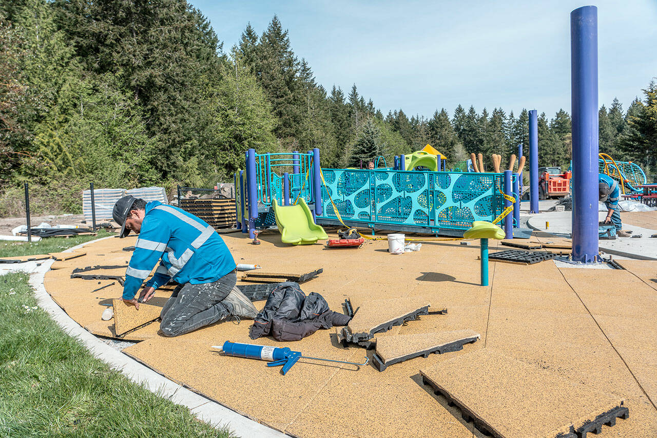 Manuel Sanchez, with MTZ Installs of Pasco, lays soft, foam tiles in the landing area of the JUMP playground area of HJ Carroll Park in Port Hadlock as part of phase two of new equipment and safety upgrades. (Steve Mullensky/for Peninsula Daily News)