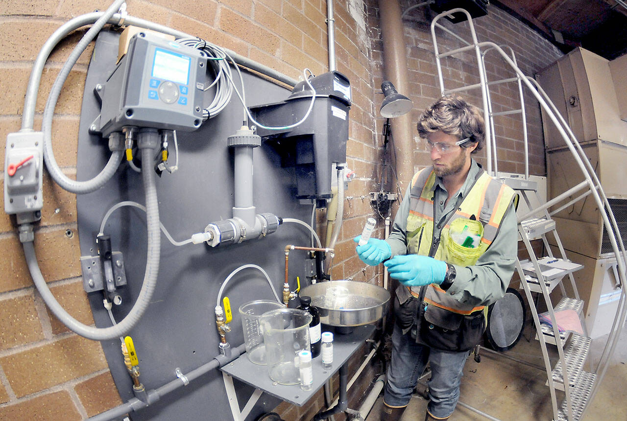 Ben Hecht, a geologist with environmental consulting firm Landau Associates, takes a sample of raw drinking water taken at the city of Port Angeles ranney collector on Saturday at the Elwha River, downstream from Fridays tanker crash that dumped petroleum products into Indian Creek west of Port Angeles. (Keith Thorpe/Peninsula Daily News)
