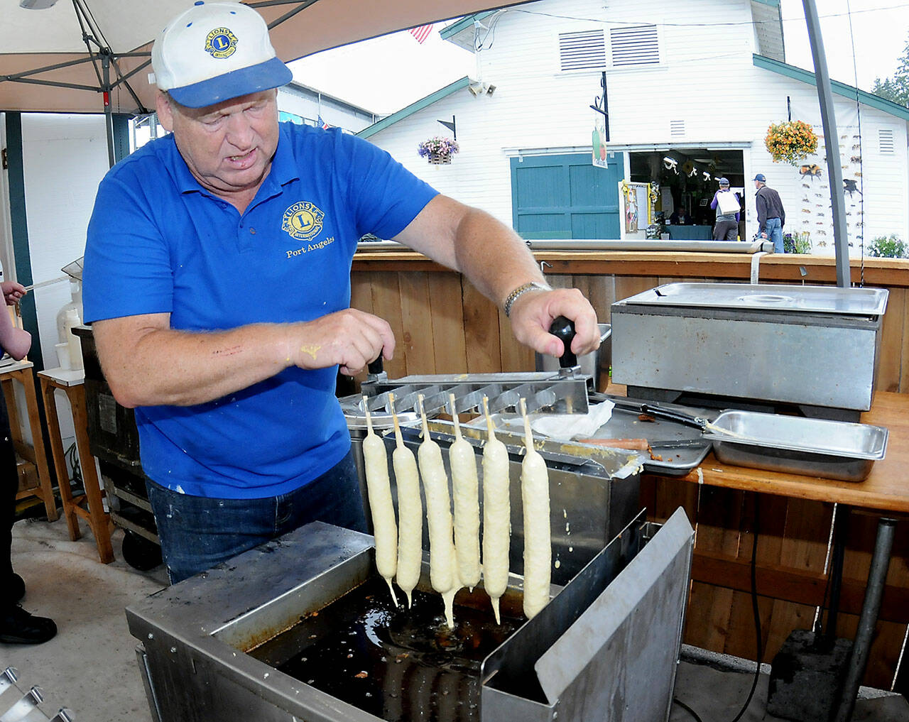 Port Angeles Lions Club member Kevin Borde dips batter-coated jumbo hot dogs into a fryer to make corn dogs at the clubs food stand at the Clallam County Fair on Friday. (Keith Thorpe/Peninsula Daily News)