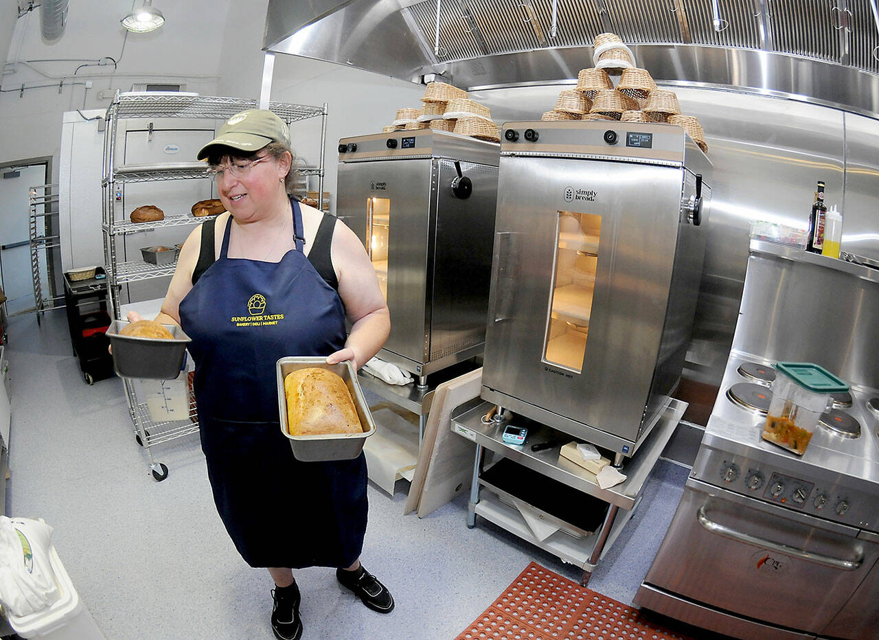 Kate Orzikh, owner of Sunflower Tastes bakery and deli at The Wharf in Port Angeles, holds loaves of sourdough bread created in the establishments kitchen. (Keith Thorpe/Peninsula Daily News)