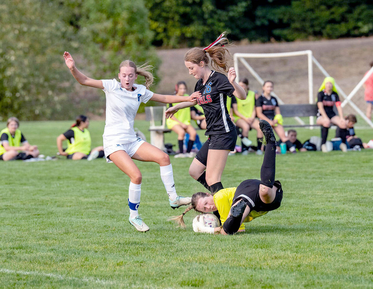 East Jeffersons goalkeeper Lila Morgan makes a diving save off the foot of Bellevue Christians Emily Eggers as the Rivals Fern French (16) is in on the play during a Nisqually League game played on Tuesday at H.J. Carroll Park in Port Hadlock. (Steve Mullensky/for Peninsula Daily News)