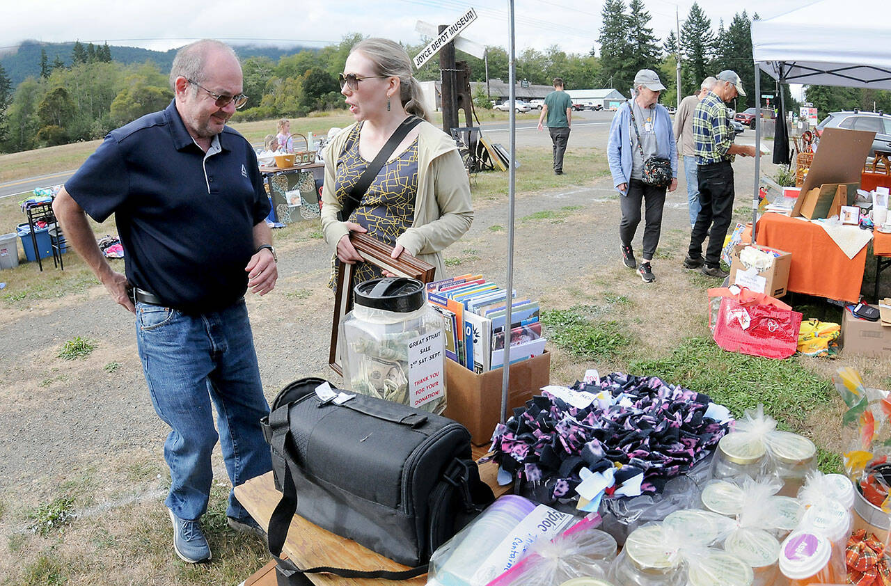 Tim Blair and Amy Peterson, both of Port Townsend, make a purchase from a table of random sale items during Saturdays Great Strait Sale at a community vending location in Joyce. The annual event featured dozens of yard and garage sales stretching along state Highway 112 from Port Angeles to Neah Bay. (Keith Thorpe/Peninsula Daily News)