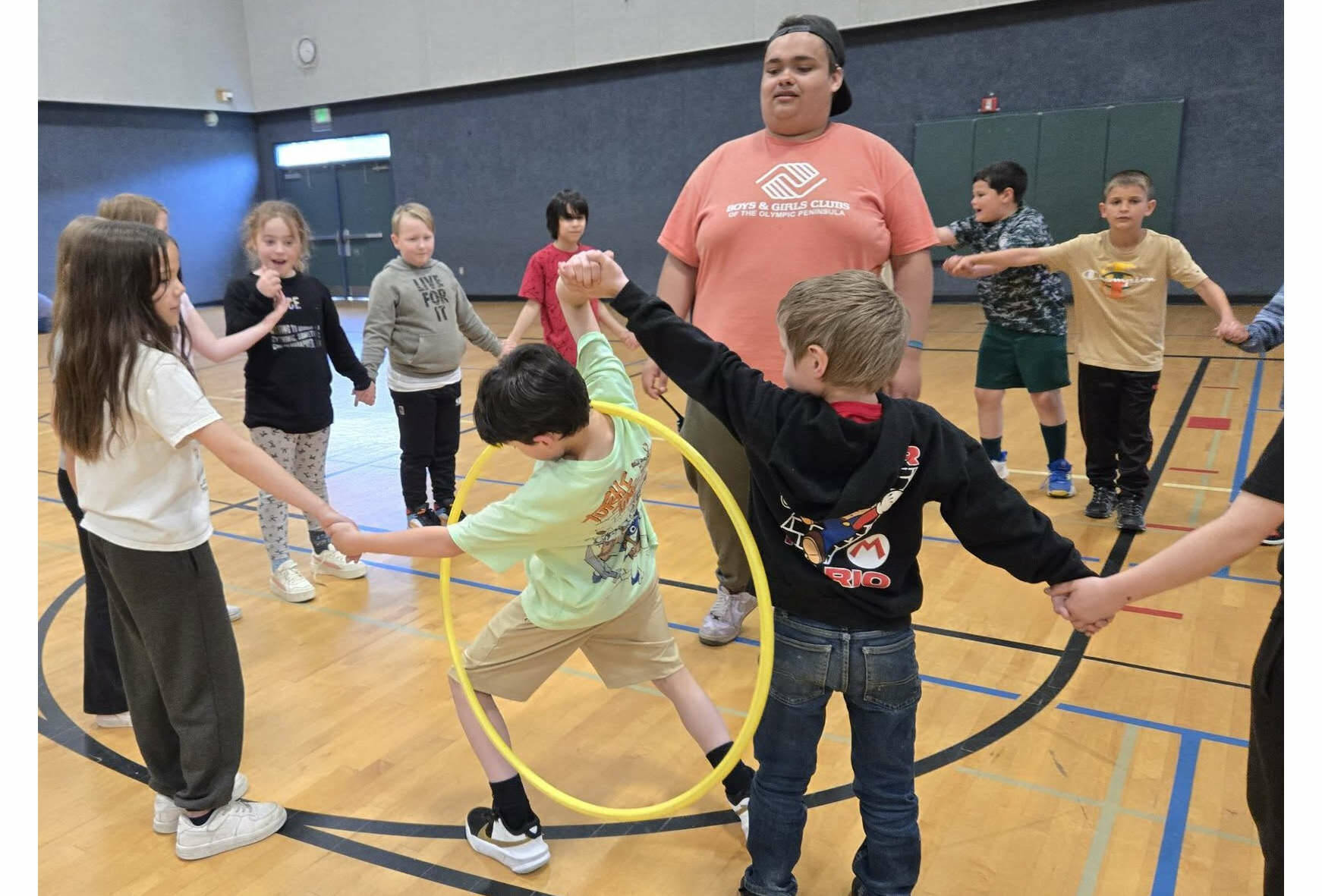 Youth Development staffer Aymon Anderson leads a group of elementary school children in a hula hoop challenge as part of the Sequim Boys & Girls Clubs Project L.A.N.E. (Boys & Girls Clubs of the Olympic Peninsula)