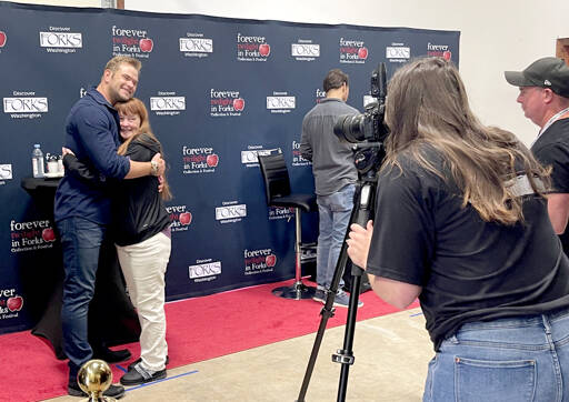 Actor Kellan Lutz, left, hugs a fan during a meet the actors photo session during the Forever Twilight Forks event on Friday. All VITs had the opportunity for a photo and to get one item signed. Lutz played Emmett Cullen in The Twilight Saga film series. Also attending were Peter Facinelli, who played Dr. Cullen, seen at right, and actor and regular participant Erik Odom. Author Stephenie Meyer attended for the first time in many years. An estimated 1,000 people attended the Q&A with Meyer and movie at the Kitla Center. (Christi Baron/Olympic Peninsula News Group)