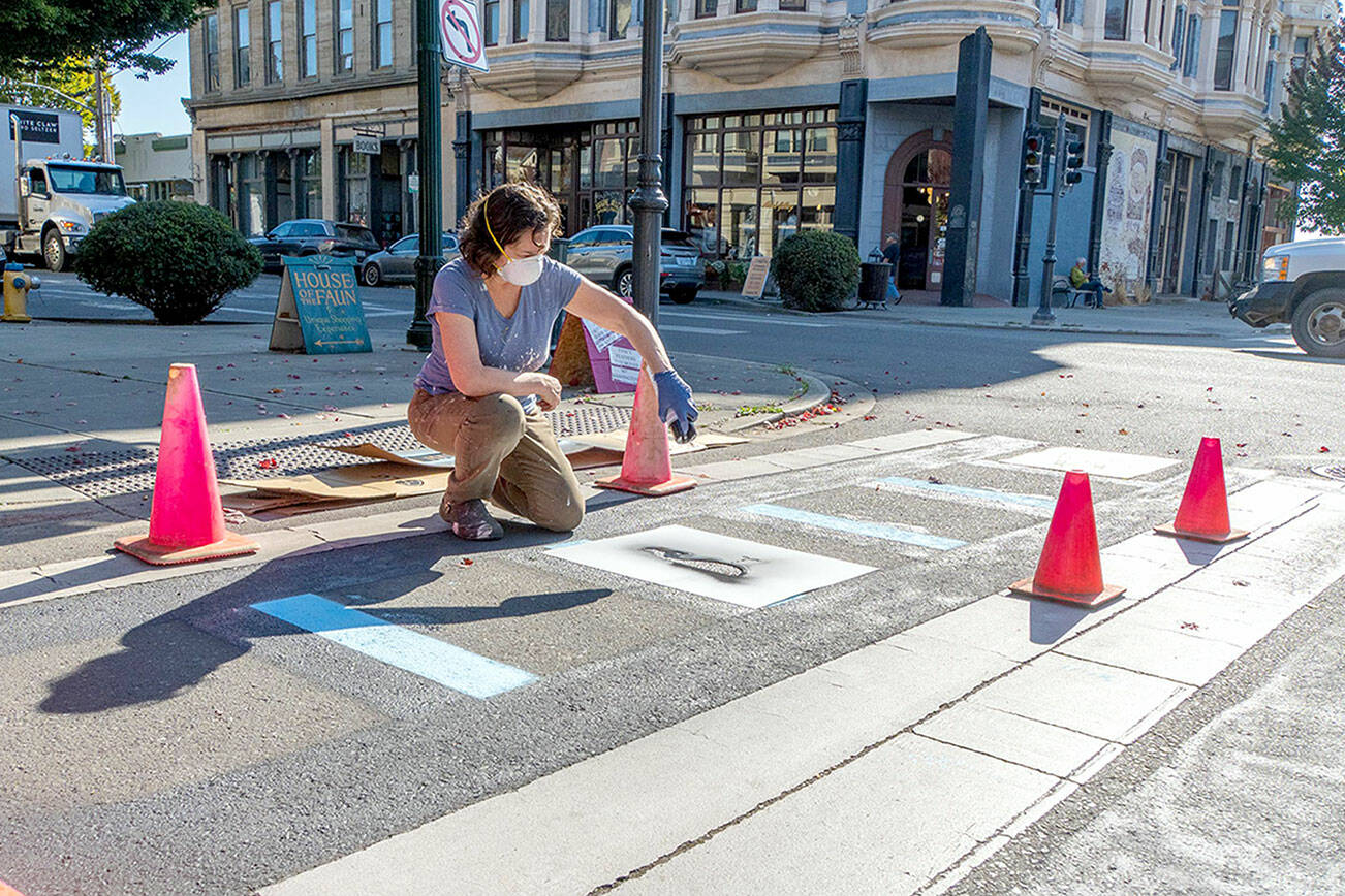 Connie Segal of Port Townsend spray paints a graphic by local artist Timbul Cahyono on the crosswalk at Taylor and Water streets in downtown Port Townsend on Wednesday. The graphics are outside the Port Townsend Film Festival’s temporary lounge on the corner and make for a light-hearted entrance to the festival, which will host its Opening Night gala tonight. Films will be screened from Friday through Sunday at various locations. (Steve Mullensky/for Peninsula Daily News)
