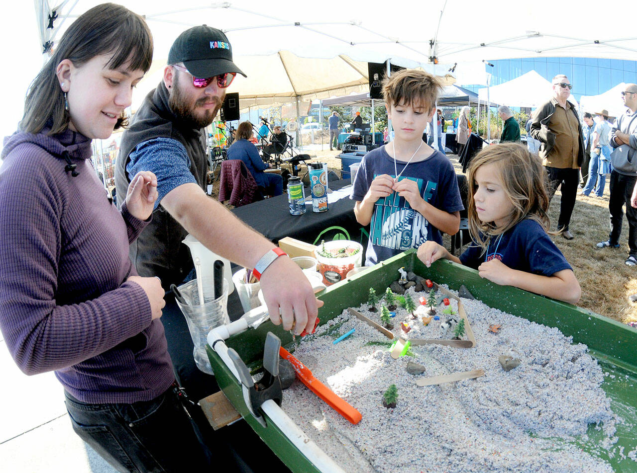 Naturebridge educators Ana Shinal, left, and Zach Drake demonstrate how water erosion affects the landscape in a test farm assembled by Wyatt Lutrz, 10, and Westley Lutz, 7, at a hands-on display set up by the Naturbridge educational organization at the fourth annual Forever StreamFest on Saturday at Pebble Beach Park in Port Angeles. The environmentally themed festival, hosted by the Port Angeles Garden Club, featured dozens of information booths, displays and youth activities, as well as food, music and a beer garden. (Keith Thorpe/Peninsula Daily News)