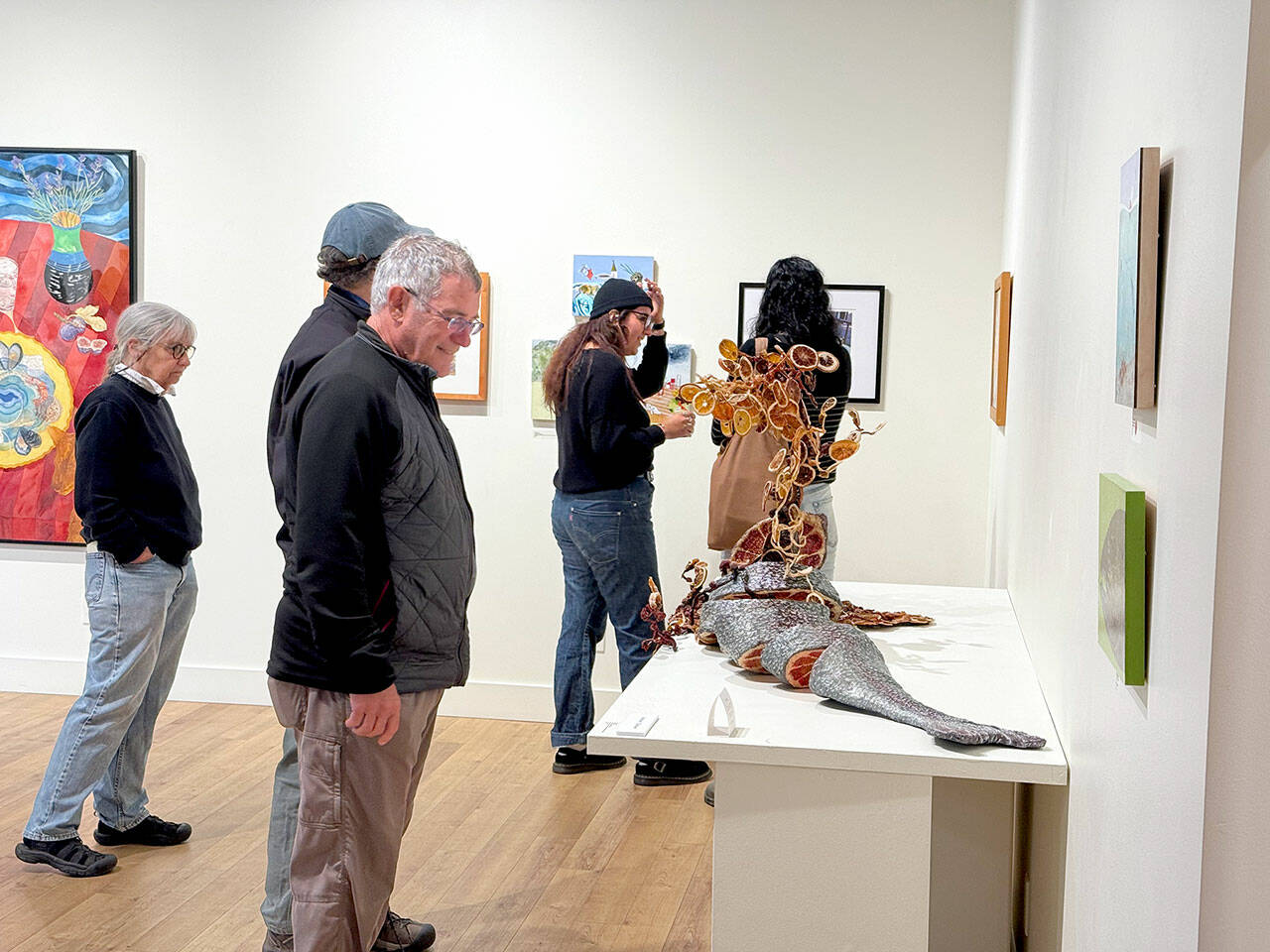 Jeanette Best Gallery visitors check out Ali Whitmores Entree Stuffed Whole Trout during Art Walk. The sculpture won the Jurors Choice and Peoples Choice awards in the recent Potluck Banquet exhibition. (Diane Urbani/Northwind Art)