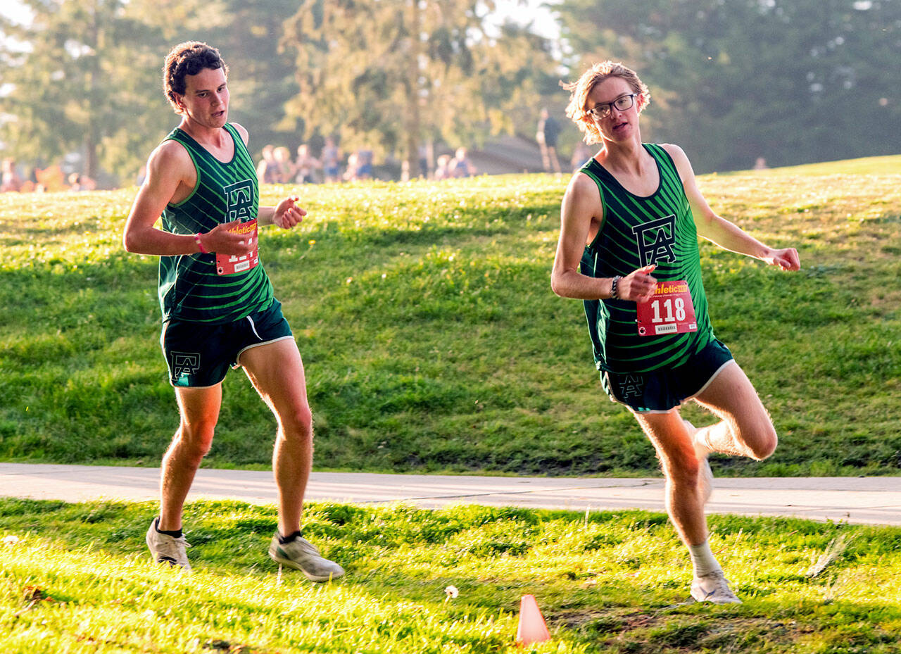 OlympicLeagueXC-PDN-251025 Emily Matthiessen/for Peninsula Daily News Port Angeles boys runners Andre Campbell, left, and Easton Dempsey round a turn during the Olympic League Cross Country Championships at The Cedars at Dungeness Golf Course on Thursday.