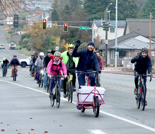 Matthew Moore, center, leads a group of Cranksgiving bicyclists on Eighth Street in Port Angeles using his specially build cargo bike to collect and transport purchased goods. The annual Cranksgiving food drive was held Saturday as 14 bike riders visited four different grocery stores and used their own money to buy food for the Port Angeles Food Bank. A total of 254 pounds was collected. A similar Cranksgiving event is scheduled for Sequim on Saturday. (Dave Logan/for Peninsula Daily News)