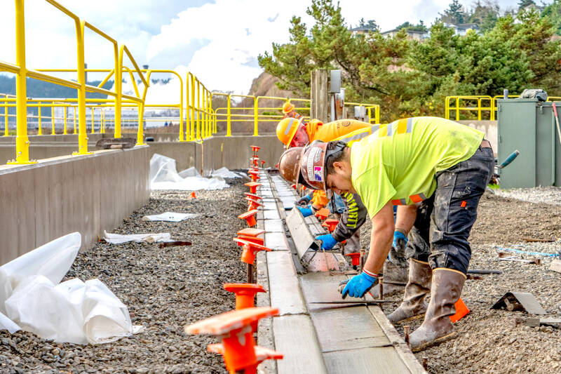 Workers from Van Ness Construction of Port Hadlock smooth out newly poured curbs and gutters on Tuesday as part of the Port of Port Townsend’s stormwater recovery system, an ongoing project at the Port Townsend Marina. (Steve Mullensky/for Peninsula Daily News)