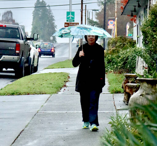 Sue Bahl walks with an umbrella on West Eighth Street on Monday. Heavy rainfall up to 8 inches over the past several days has increased the threat of landslides in Western Washington, according to the National Weather Service. A flood watch also has been issued until 4 p.m. Friday for portions of northwest and west central Washington, including Clallam and Jefferson counties. Sharp rises in rivers, especially those flowing off the Olympics and Cascades, are expected, the National Weather Service said. (Dave Logan/for Peninsula Daily News)