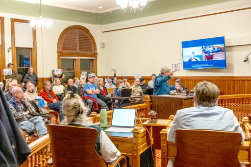 Judy Krebs of Port Townsend speaks to the Port Townsend City Council on Monday to voice her concerns regarding the councils pending vote on the 2026 Comprehensive Plan and development regulations. Krebs holds a sign that reads pause, as do others, entreating the council to delay its vote on passing the plan. About 65 citizens filled the chamber to capacity for the meeting. (Steve Mullensky/for Peninsula Daily News)