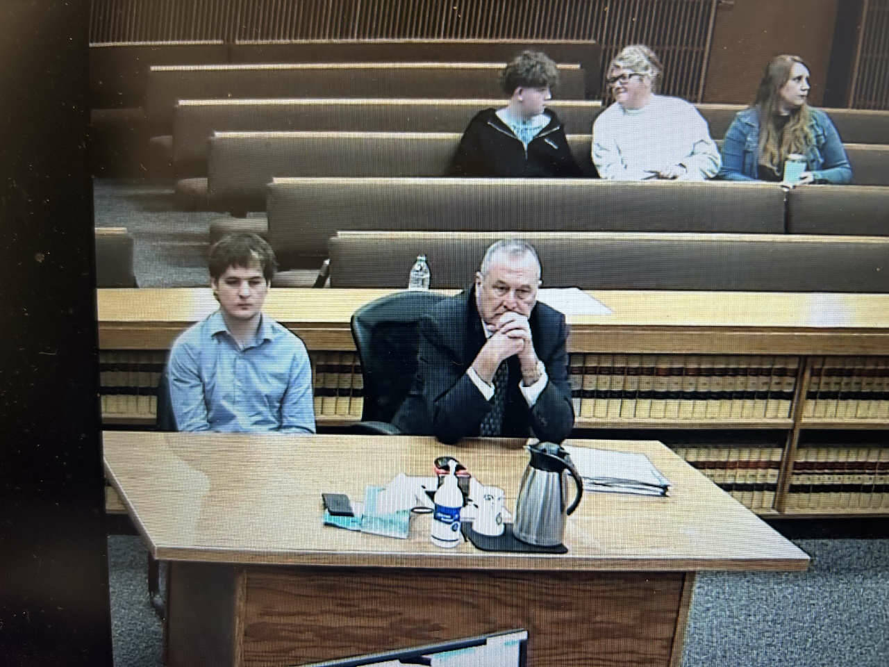 Cole Douglas, who was sentenced Thursday after he pleaded guilty to the March 2025 hit and run that seriously injured Sequim middle-schooler Colton Dufour, listens to Judge Elizabeth Stanley as Coltons mother, Cherie Tachell, seated several rows back, smiles at her son just minutes before Douglas was taken into custody to begin serving a 12-month jail sentence. Seated beside them is victims advocate Molly Ramsey, who works in the Clallam County prosecuting attorneys office and read a victims impact statement to the court during hearing. (Clallam County Superior Court)