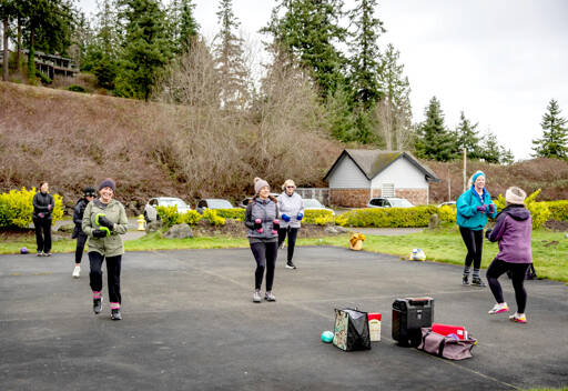 TJ Plastow, right, in purple coat, leads Lets Keep Moving, an outdoor fitness class at Port Ludlow Marina on Friday. The class participants are known to show up in all weather. On Friday, it was 40 degrees and breezy. (Steve Mullensky/for Peninsula Daily News)