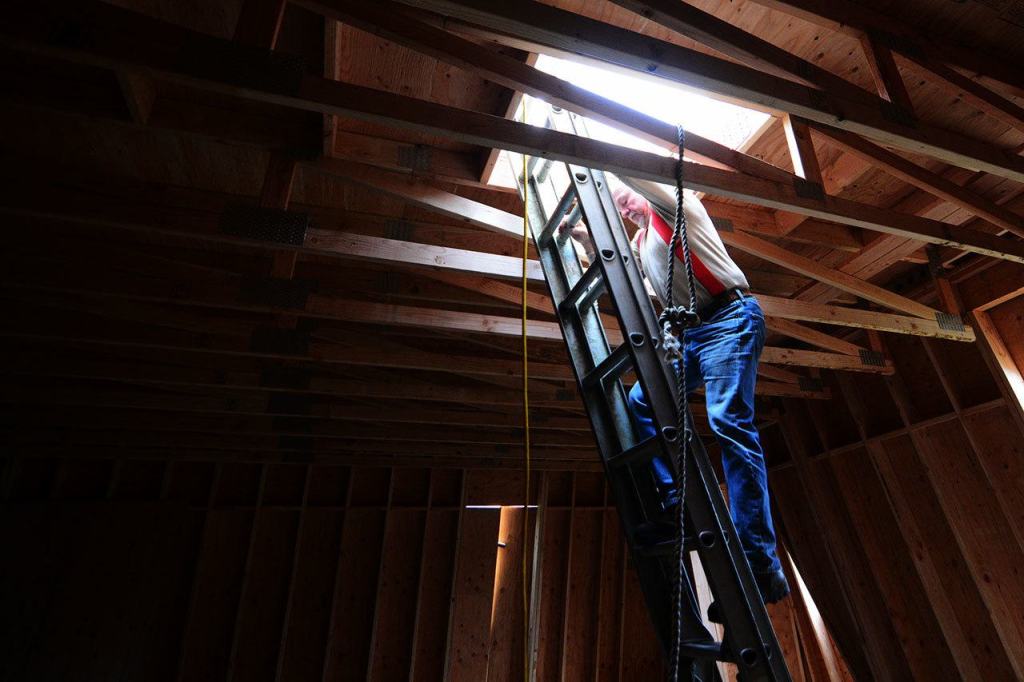 Dave Satterlee, a Quilcene Historical Museum board member, climbs down from the roof of Quilcene&rsquo;s Worthington Mansion on Wednesday. (Jesse Major/Peninsula Daily News)