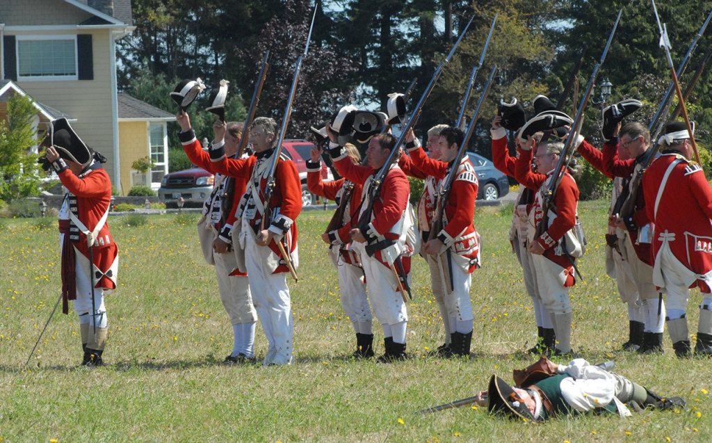 A killed colonial militaman portrayed by John McTernan of Kirkland lies on the ground as British soldiers salute King George III as part of a reenactment of the Battle of Lexington Green. (Keith Thorpe/Peninsula Daily News)