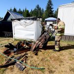 East Jefferson Fire-Rescue firefighter DeAndrew Wesley overhauls an outbuilding that caught fire in Olympic Trailer Park near Port Townsend on Tuesday. (Jesse Major/Peninsula Daily News)