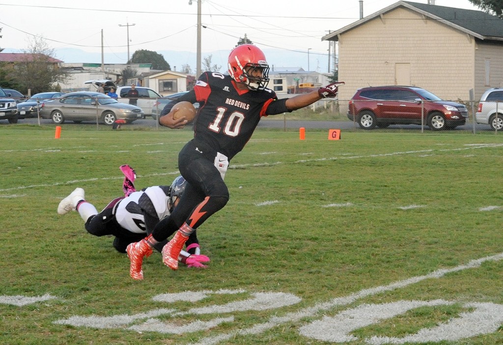 Lonnie Archibald/for Peninsula Daily News Neah Bay quarterback Rwehabura Munyagi Jr. avoids the grasp of a Tulalip Heritage tackler and points upfield during a 2015 game.