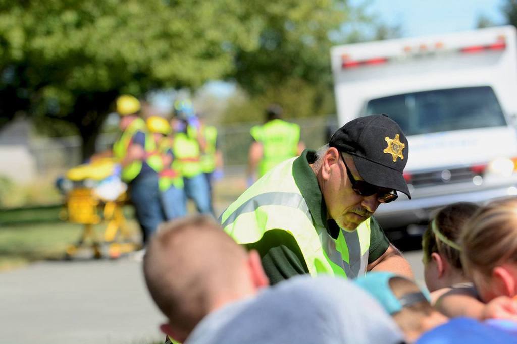 Tim Richards, a chaplain with the Clallam County Sheriff&rsquo;s Office, comforts children during a mass shooting drill at Greywolf Elementary School in Sequim on Friday. (Jesse Major/Peninsula Daily News)