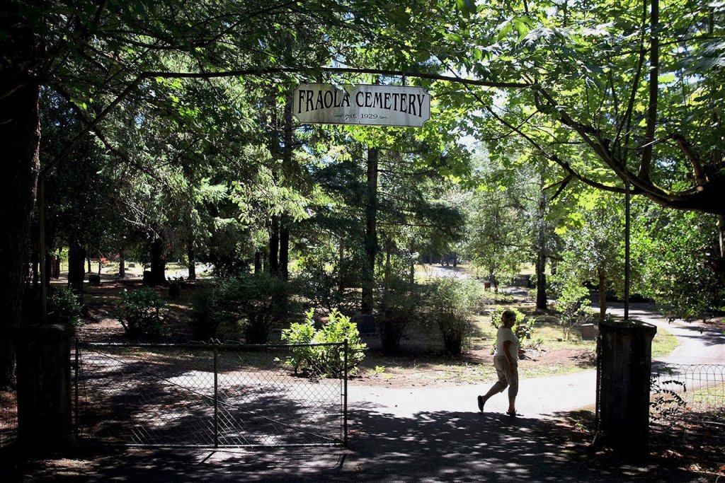 Joanne Clark, the secretary/treasurer for the Fraola Cemetery, closes the gate of the cemetery in Olalla on Aug. 5. The Fraola Cemetery, established in 1929, is still used for burials. (Larry Steagall/Kitsap Sun via AP)