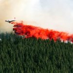 A plane drops fire retardant on the north side of Beacon Hill on Sunday in Spokane. The fast moving wildfire is threatening structures as it moves in a northeasterly direction. (Colin Mulvany/The Spokesman-Review, via AP)