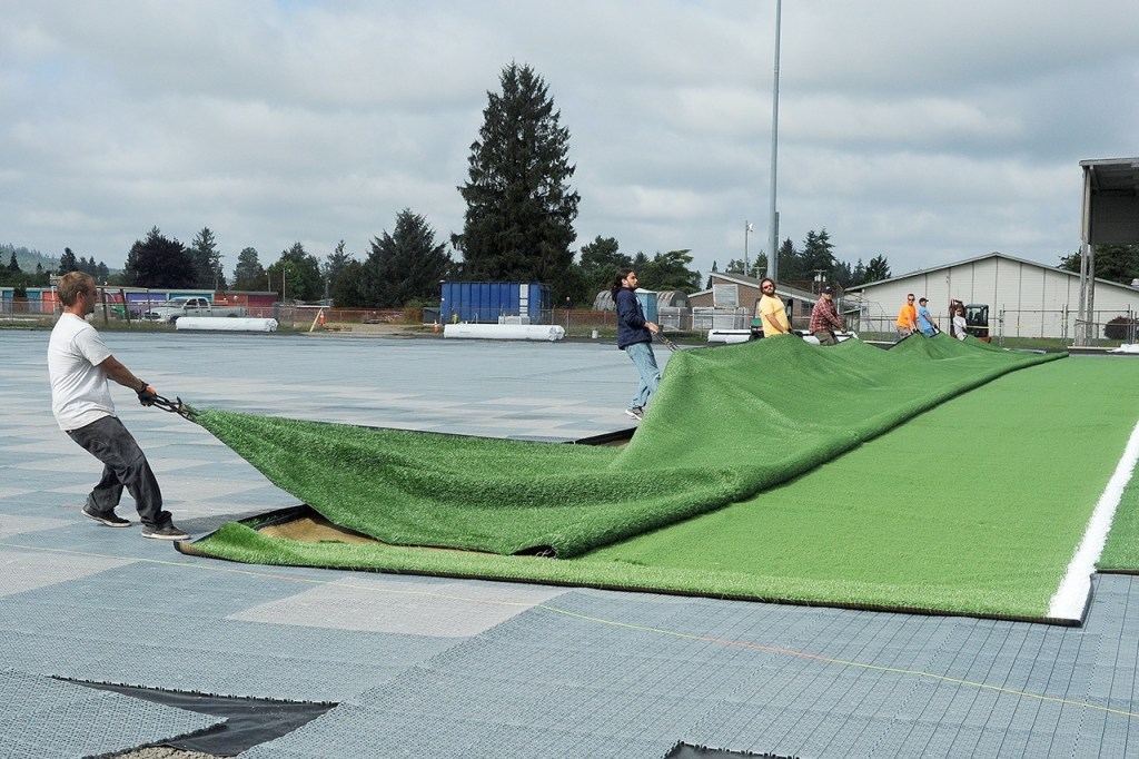 Lonnie Archibald/for Peninsula Daily News Workers drag a section of turf onto the Spartan Stadium field last month. The first game on Forks&rsquo; brand-new FieldTurf playing surface will be played against Vashon Friday at 7 p.m.