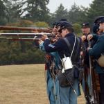 Cydney McFarland/Peninsula Daily News                                Members of the Company C 4th U.S. Infantry Civil War re-enactors group fire blank rounds on the field at Fort Worden during a performance Monday afternoon.