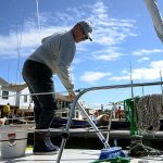 Dan Parnel of Auburn swabs the deck of his boat the Susan Joanne in preparation for the Wooden Boat Festival in Port Townsend. (Cydney McFarland/Peninsula Daily News)