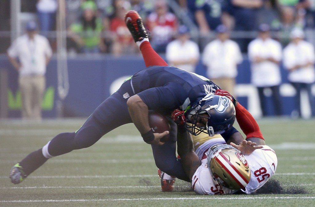 The Associated Press                                Seattle quarterback Russell Wilson, top, sprained the MCL in his left knee on this tackle by San Francisco&rsquo;s Eli Harold during the Seahawks 37-18 win over the 49ers on Sunday.
