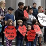 A group of people supporting public schools and opposed to further sanctions against the state regarding a lawsuit over education funding stands on the steps of the Temple of Justice in Olympia on Wednesday. (Ted S. Warren/The Associated Press)