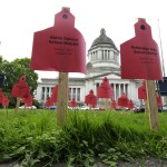 Signs naming the student and teacher populations of school districts in Washington state are shown with the Legislative Building in the background on Wednesday in Olympia prior to a state Supreme Court hearing on a lawsuit against the state regarding education funding. The signs were placed by a group supporting public schools and opposed to further sanctions against the state regarding the lawsuit. (Ted S. Warren/The Associated Press)