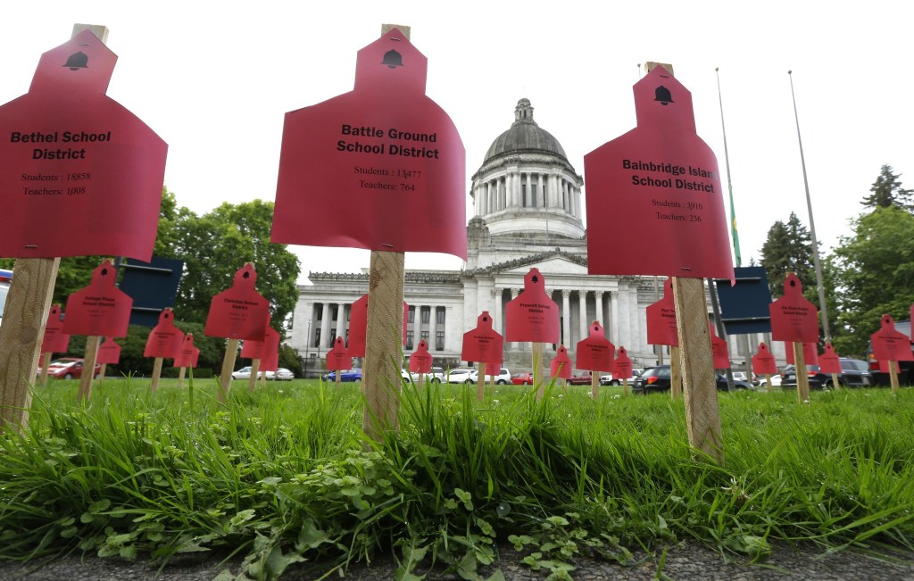 Signs naming the student and teacher populations of school districts in Washington state are shown with the Legislative Building in the background on Wednesday in Olympia prior to a state Supreme Court hearing on a lawsuit against the state regarding education funding. The signs were placed by a group supporting public schools and opposed to further sanctions against the state regarding the lawsuit. (Ted S. Warren/The Associated Press)