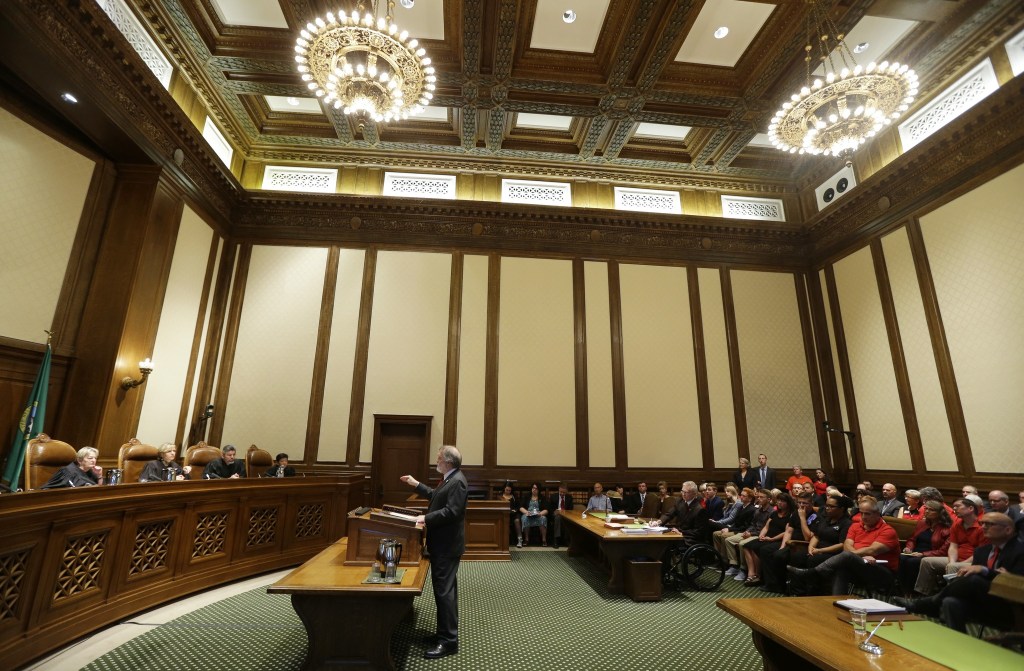 Alan Copsey, center, a deputy attorney general for the state of Washington, speaks during a hearing before the state Supreme Court regarding a lawsuit against the state over education funding on Wednesday in Olympia. (Ted S. Warren/The Associated Press)