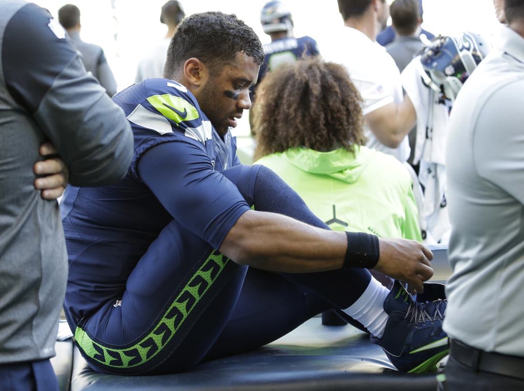 Seattle Seahawks quarterback Russell Wilson laces his shoe after getting his ankle taped following a play during the second half of an NFL football game against the Miami Dolphins, Sunday, Sept. 11, 2016, in Seattle. (AP Photo/Elaine Thompson)