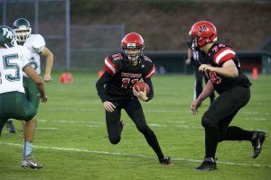 Steve Mullensky/for Peninsula Daily News Port Townsend &lsquo;s Berkley Hill, with ball, plants a foot and dodges the tackles of a pair of Port Angeles Roughriders during a game played in Port Townsend on Thursday.