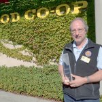 Port Townsend Co-op facilities manager Rene Tanner stands in front of the co-op with last year&rsquo;s trophy from the EPA GreenChill program. The co-op has been awarded two years in a row for its efforts in lowering its refrigerant emissions. (Cydney McFarland/Peninsula Daily News)