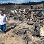 Vern Scherrer, 83, walks through the burned remains of his rental property near Wellpinit on Aug. 25. (Colin Mulvany/The Spokesman-Review via AP)
