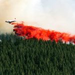 A plane drops a load of fire retardant on the north side of Beacon Hill, in Spokane on Aug. 21. (Colin Mulvany/The Spokesman-Review, via AP)