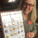 Gloria Skovronsky, president of the Peninsula Button Club, shows a shadow box display with buttons from her collection. The club is hosting the Washington State Button Society Convention and Show for the first time in Sequim today and Saturday. (Mary Powell)
