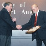 Port Angeles Mayor Dan Di Guilio, left, congratulates outgoing City Council Member and Deputy Mayor Don Perry at a City Council meeting. Perry was honored for his service as council member and for serving two years as deputy mayor. (Keith Thorpe/Peninsula Daily News)