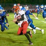Steve Mullensky/for Peninsula Daily News Port Townsend&rsquo;s Berkley Hill tries to evade the tackles by Chimacum&rsquo;s Domenick Zack, 21 and Issac Purser, 83, during the Redhawks&rsquo; 55-6 win over the Cowboys. Hill scored six touchdowns in the win.