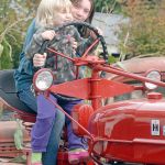 Madisyn Heistand, 10, and Abigaile Heistand, 3, both of Port Angeles, sit at the controls of an antique tractor at Agnew Grocery on Saturday. The grocery was one of seven farms and businesses taking part in the 20th annual Clallam County Farm Tour, a celebration of the agricultural heritage of the Dungeness Valley. (Keith Thorpe/Peninsula Daily News)