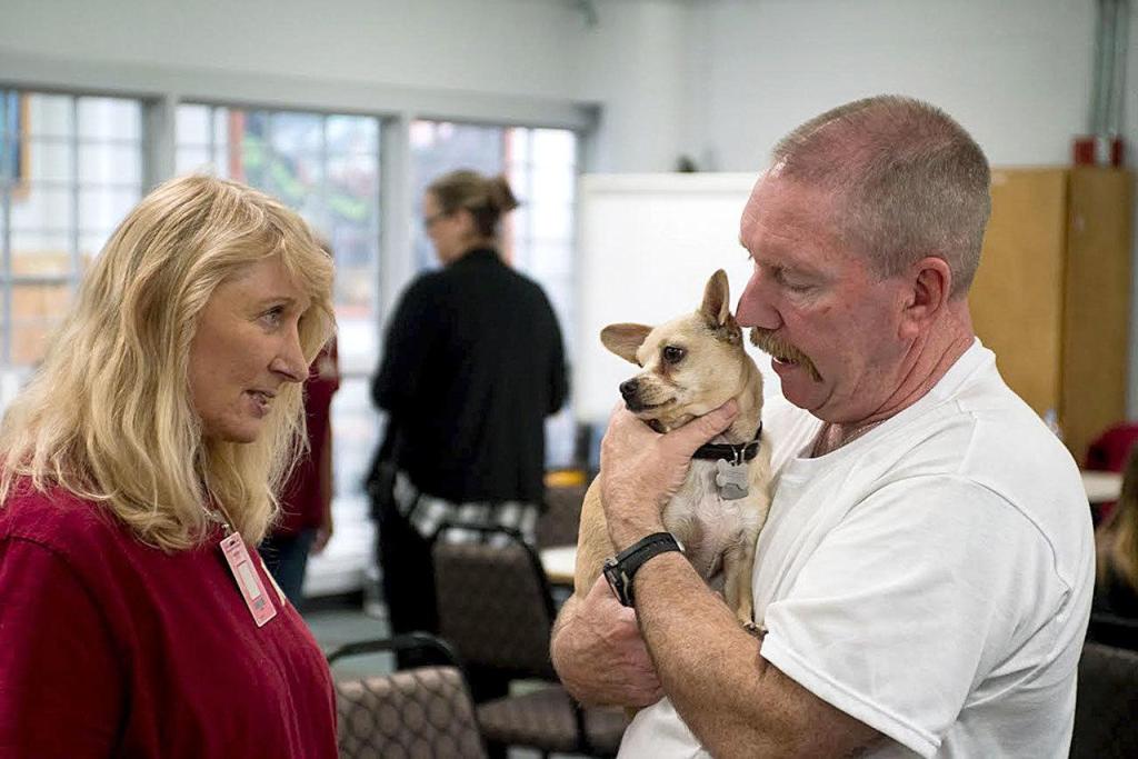 Welfare for Animals Guild volunteer Chris Clark talks to inmate Douglas Gallagher, who is holding Skeeter, a dog he trained. (Brian Harmon)